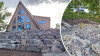 A-framehus med stor stenmur och serpentinbacke ner mot en mindre byggnad.