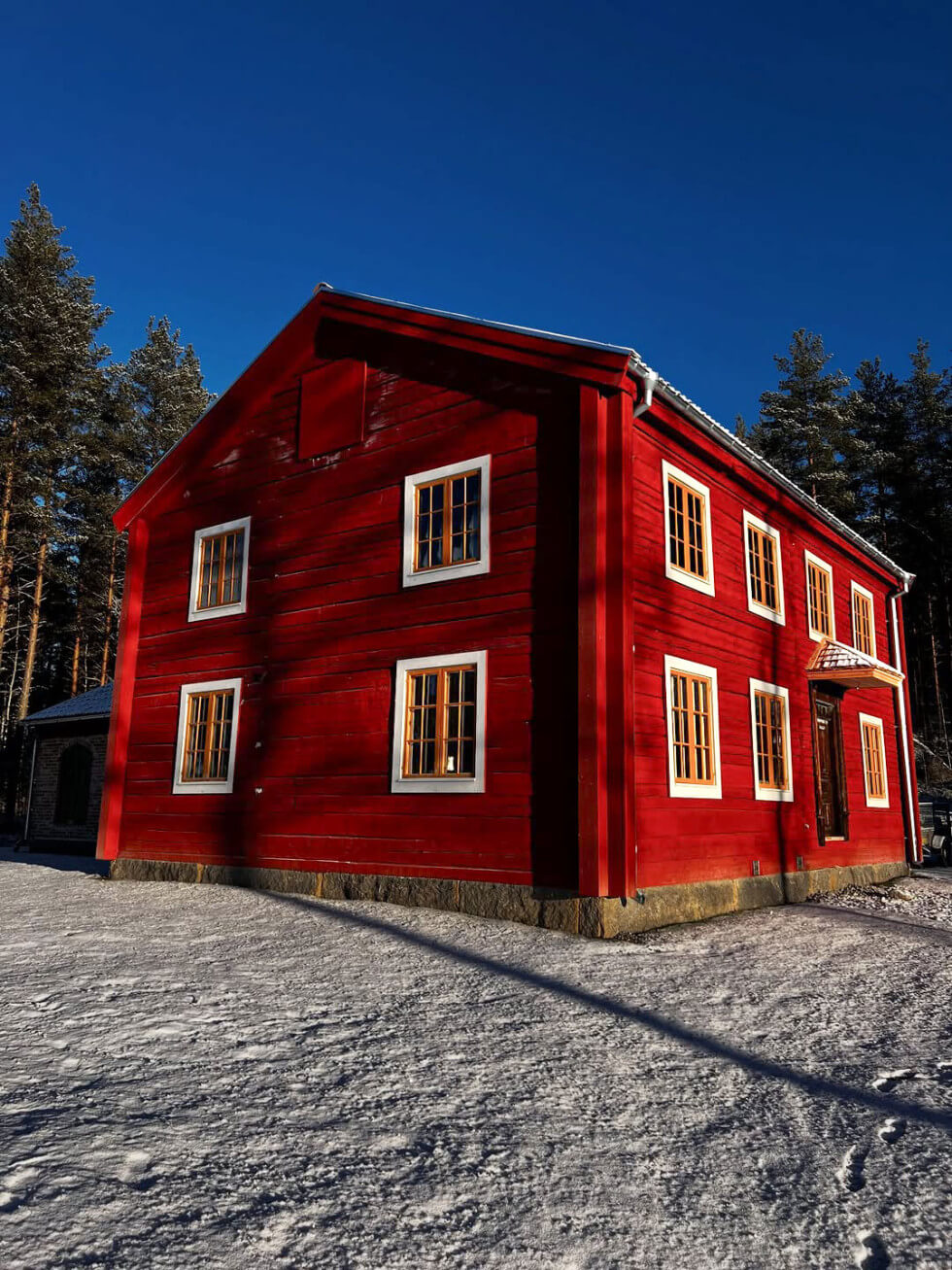 Rött timmerhus med skog i bakgrunden