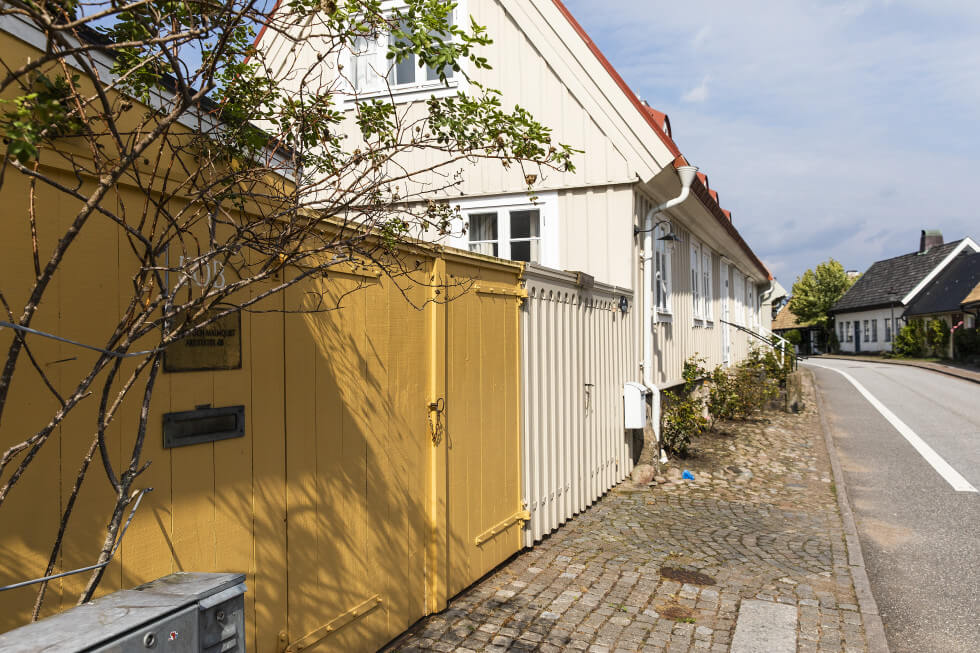 Bild från gatan på ett vitt hus med gult plank utanför