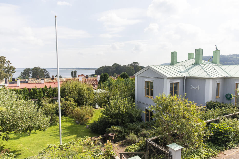 Huset i båstad med flaggstång på tomten och havsutsikt.