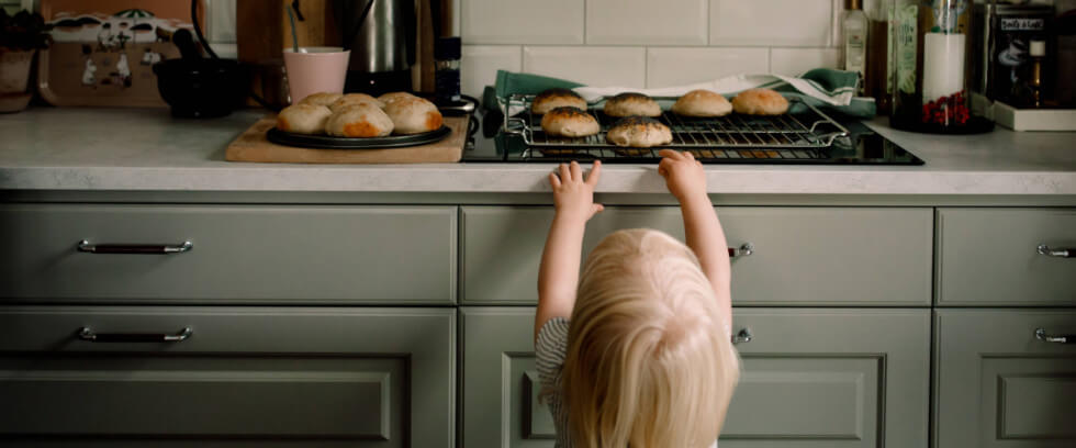 Ett barn som tar nybakade bullar i ett kök.
