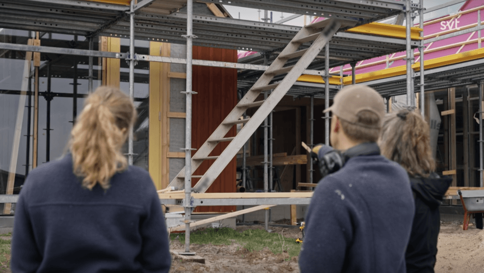 tre personer pekar på ett hus