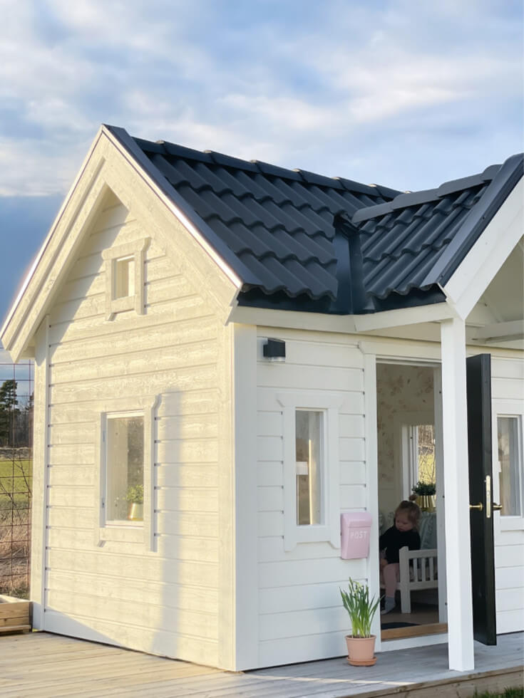 Lekstuga som är vit med en rosa brevlåda.