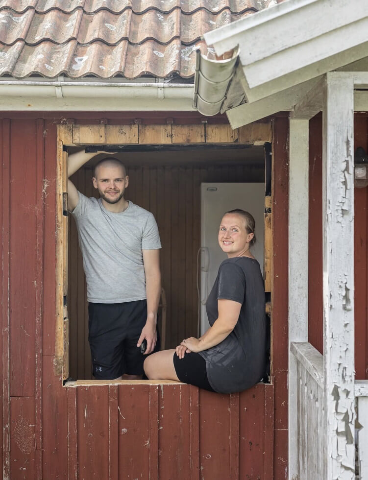 Bild på Julia Nilsson och Henke karlsson som syns genom ett fönsteröppning, utan förnster i.