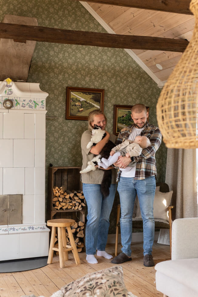 Familjen står innomhus i vardagsrummet, och Henke håller i dottern Esther och Julia i katten.