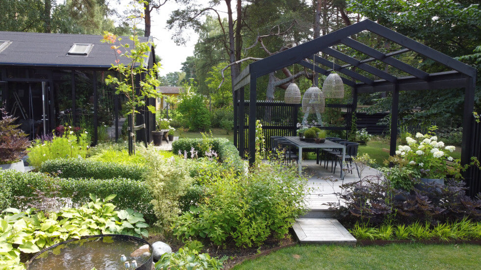 Bild på huset, trädgården och pergolan med matplats.