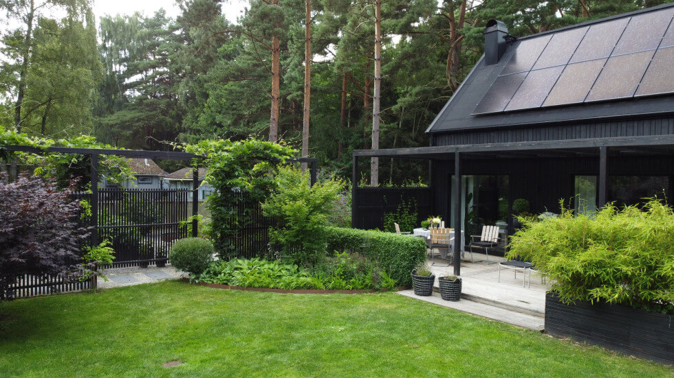 Bild på huset och trädgården där pergolan som sitter fast i huset syns.
