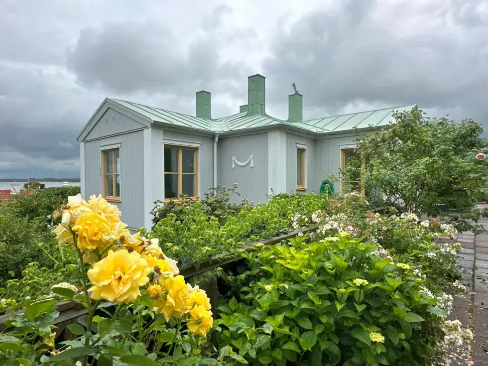 Hus från sidan med gula blommor i förgrunden.