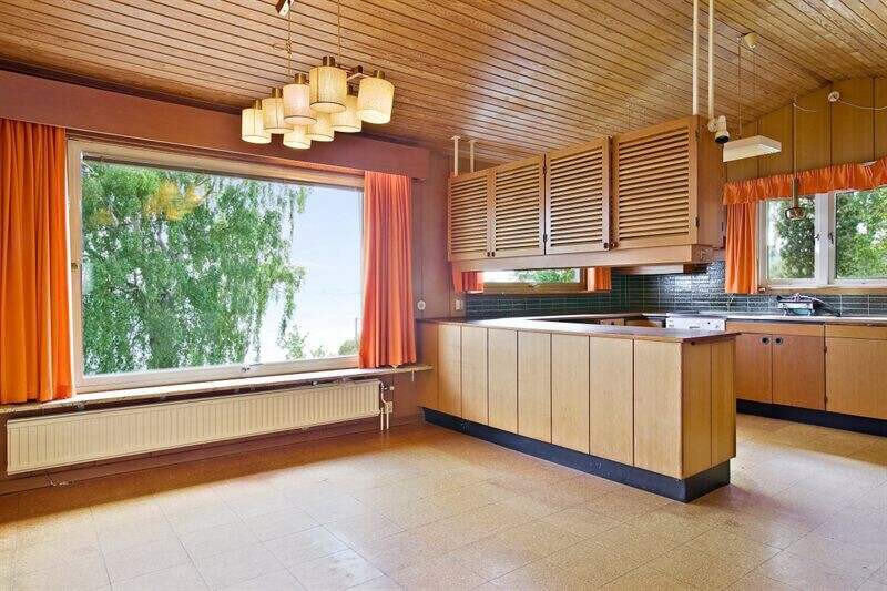Ett härligt originalkök från 70-talet med korkgolv, “titta under”-bar, grönt kakel, träpanel och orangea gardiner. 