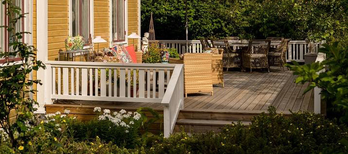 Fint vitt altanräcke av trä som matchar stilen på huset.