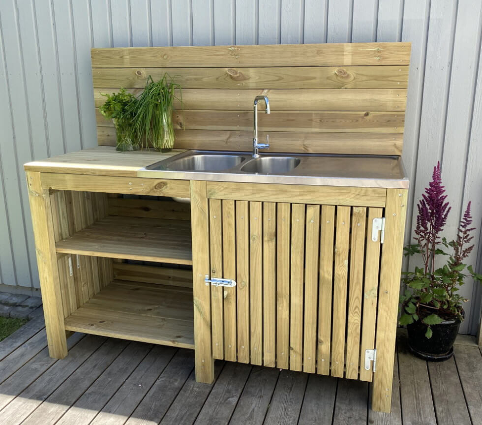 Ett utekök i tryckimpregnerat med plats för dels en kokplatta, dels en rostfri diskbänk. Här finns också ett stänkskydd mot husväggen.