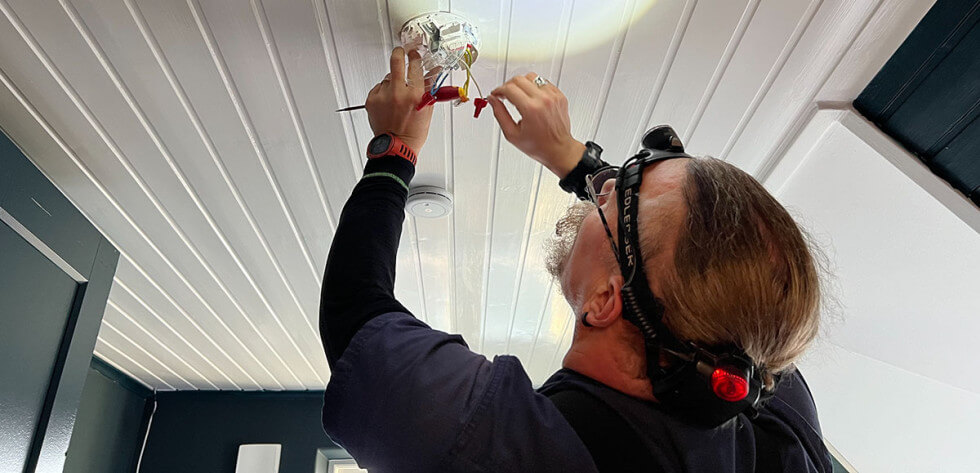Elektrikern Magnus installerar en lampa i taket.